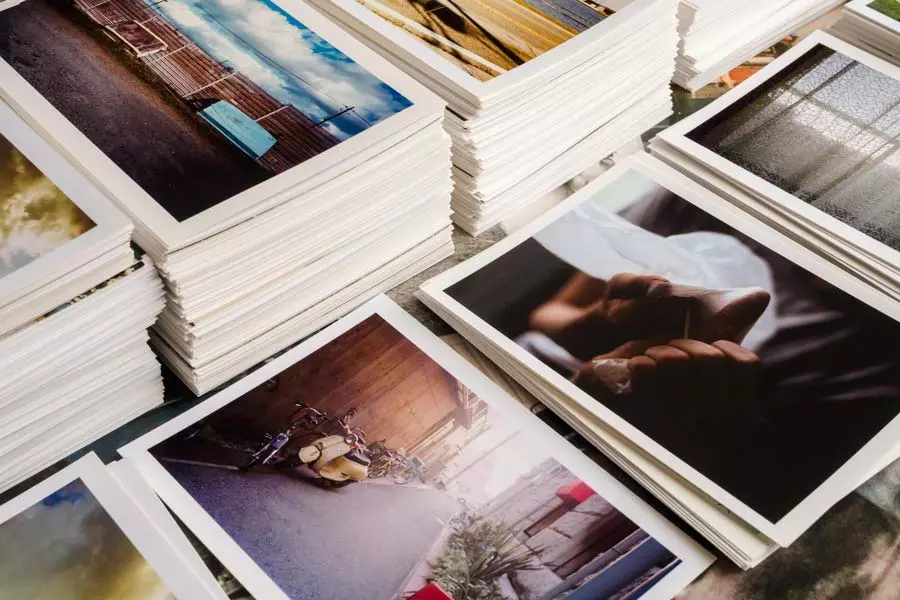 Una serie di foto stampate disposte ordinatamente su un tavolo, mostrando paesaggi e dettagli affascinanti, creando un'atmosfera di nostalgia e creatività.
